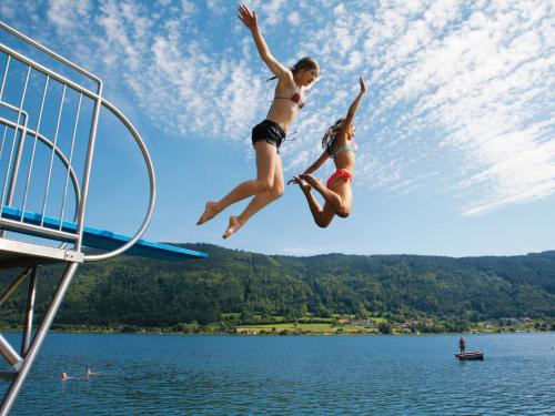 dwie dziewczyny skaczące z deski do nurkowania w wodzie w obiekcie Seehotel Hoffmann w mieście Steindorf am Ossiacher See