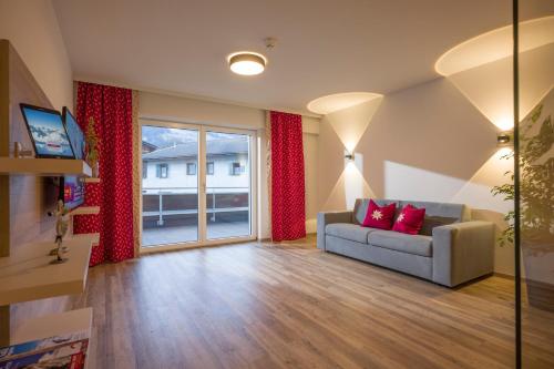 a living room with a couch and a large window at Aparthotel AlpTirol in Kaltenbach