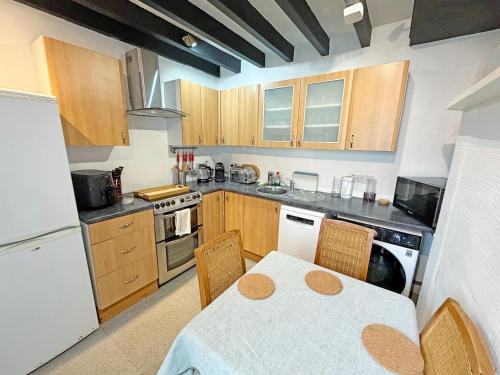 a kitchen with a table and chairs and a kitchen with wooden cabinets at The Courtyard Cottage in Llangollen