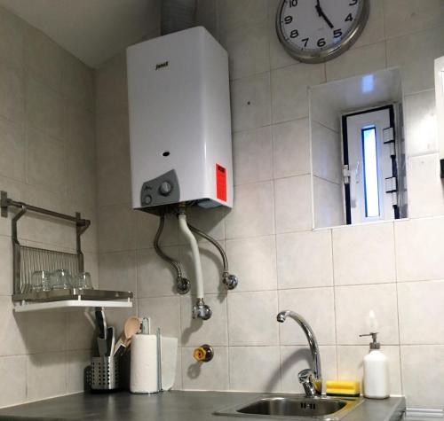 a kitchen with a sink and a clock on the wall at Casa de Cima in Lisbon