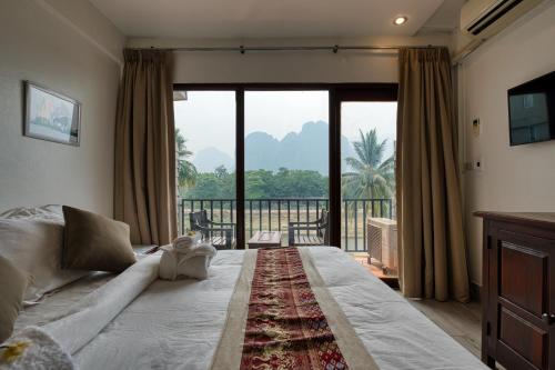 a bedroom with a large bed and a large window at The Elephant Crossing Hotel in Vang Vieng