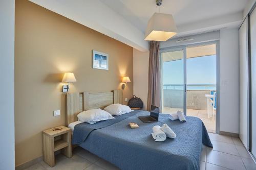 a bedroom with a blue bed with a view of the ocean at Résidence Odalys Le Lotus Blanc in Le Barcarès