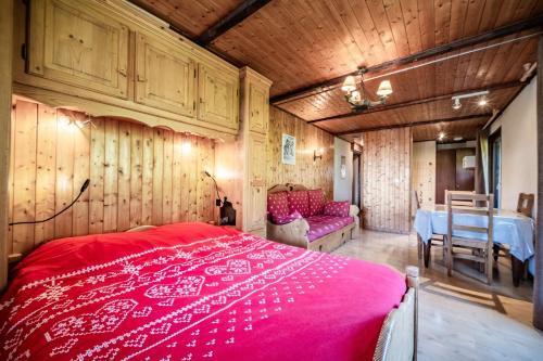 una camera da letto con un letto rosso in una stanza con un tavolo di Les Cornettes de Bise a La Chapelle-dʼAbondance