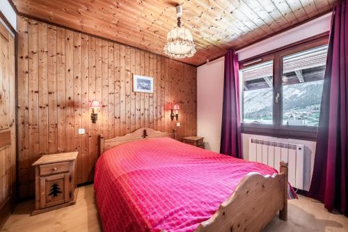 a bedroom with a bed with a pink bedspread at La Pointe des Mattes in La Chapelle-dʼAbondance