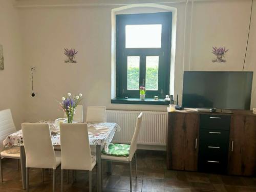 a dining room with a table with chairs and a television at Levendulásház Palkonya in Palkonya