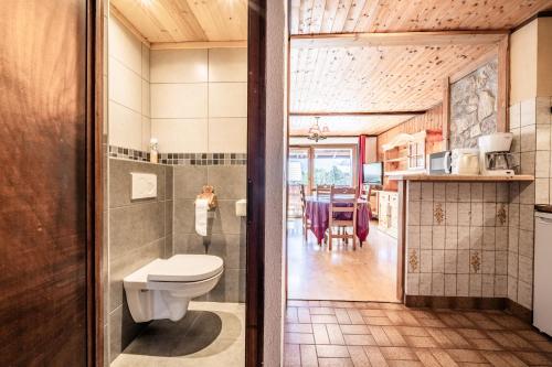 a bathroom with a toilet and a dining room at La Pointe des Mattes in La Chapelle-dʼAbondance
