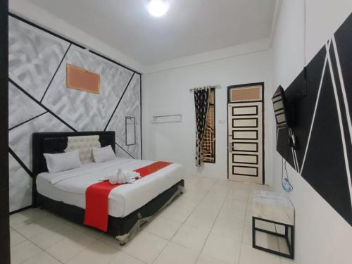 a bedroom with a bed with a red and white blanket at Dnaiko Syariah Hotel in Bukittinggi