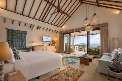 a bedroom with a large white bed and a living room at Eliana Resort And Spa in Nembrala