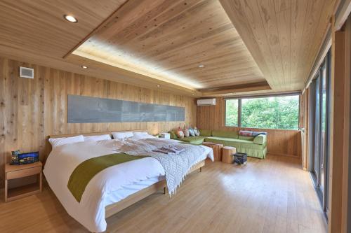 a bedroom with a large bed and a green couch at Kisara Oneness in Toba