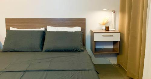 a bed with two pillows and a night stand next to it at Be Residences Studio in Cebu City