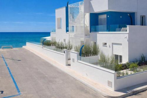 a white building with the ocean in the background at Hotiday Rooms Torre Pali in Torre Pali