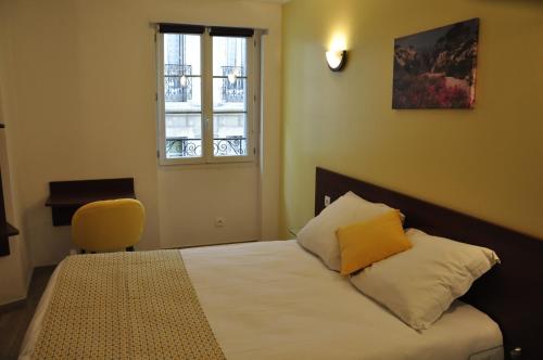 a bedroom with a bed with a yellow pillow and a window at Massilia hôtel in Marseille