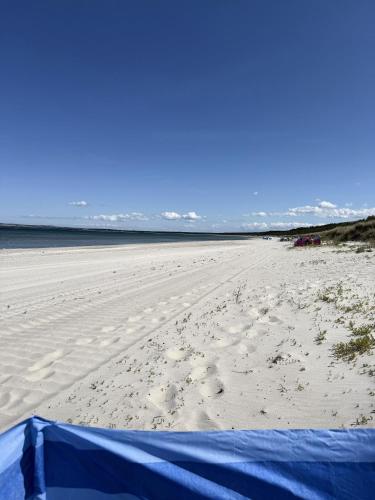 a sandy beach with a blue tent on it at Ferienwohnung Sternenhimmel in Dranske