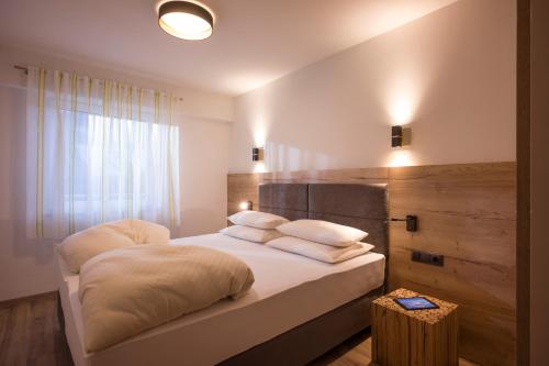 a bedroom with a bed with white sheets and a window at Aparthotel AlpTirol in Kaltenbach