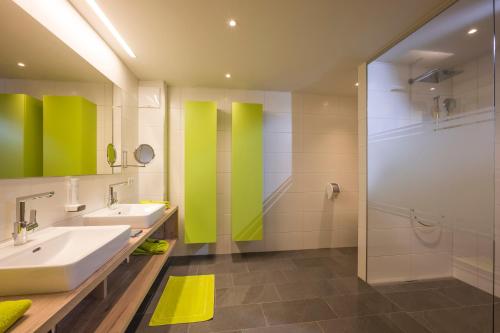 a bathroom with two sinks and a shower at Aparthotel AlpTirol in Kaltenbach