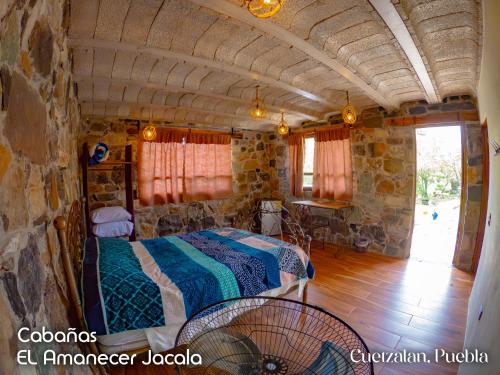 a bedroom with a bed in a stone building at Cabañas el amanecer Jacala in Cuetzalán del Progreso