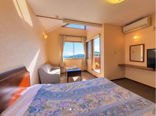 a bedroom with a bed and a chair and a window at Nasubi no Hana in Ito