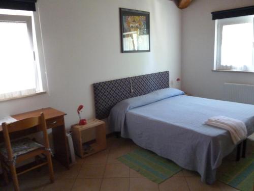 a bedroom with two beds and a desk and two windows at alla Gledizia in Udine