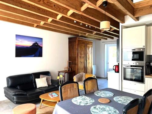 a living room with a table and a black couch at Cottage Le Phare in Mont-Dol