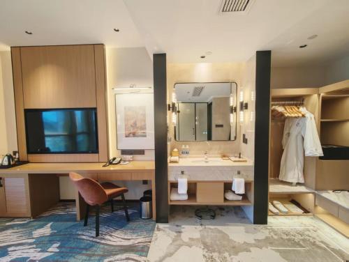 a bathroom with a sink and a desk with a mirror at Sheraton Chongqing Hotel in Chongqing