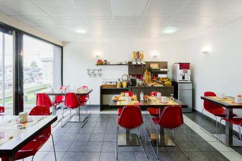 a restaurant with red chairs and tables and a kitchen at Aparthotel Adagio Access Orléans in Orléans