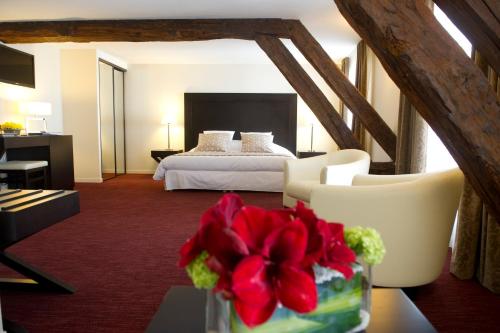 ein Hotelzimmer mit einem Bett und einer Vase mit roten Blumen in der Unterkunft Hôtel Burgevin in Sully-sur-Loire