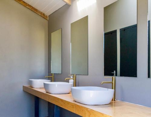 two sinks in a bathroom with two mirrors at Bietjiedam's Campsites in Caledon