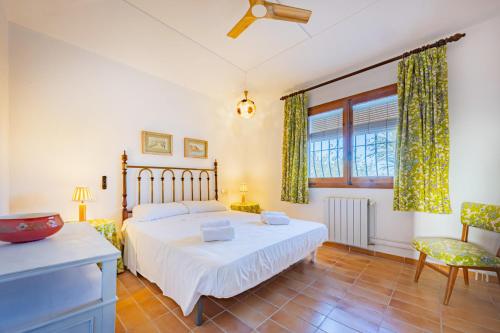 a bedroom with a bed and a chair and a window at Villa Mas Blanc - PlusHolidays in Benissa