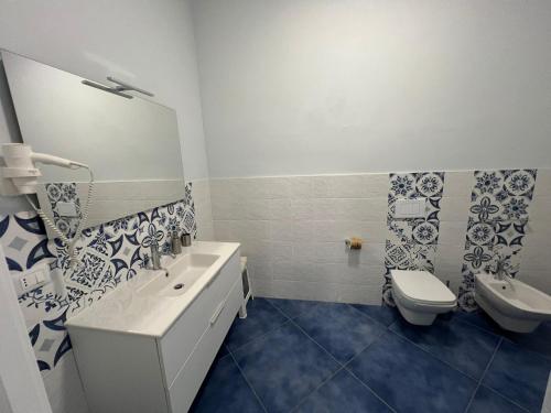 a white bathroom with a toilet and a sink at Hotel La Giara in Zambrone