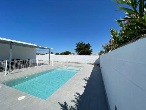 a swimming pool next to a white wall next to a building at Casa Miamar II in Campano