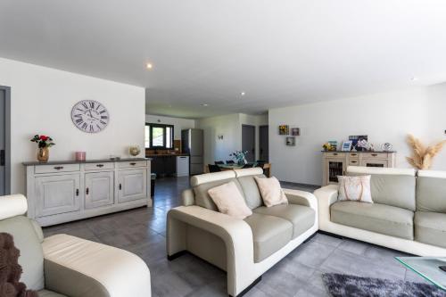 ein Wohnzimmer mit zwei Sofas und einer Uhr an der Wand in der Unterkunft Maison Lahourcade in Lahourcade