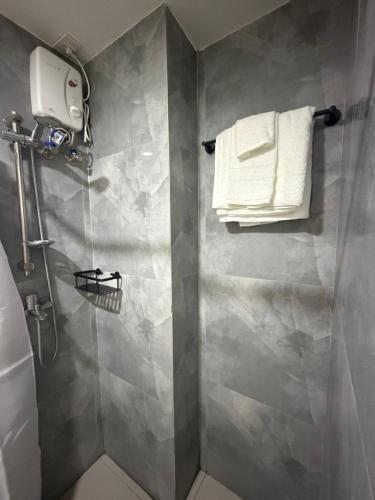 ein Badezimmer mit Dusche und Handtüchern an der Wand in der Unterkunft Ana condo at Primeworld District in Agus