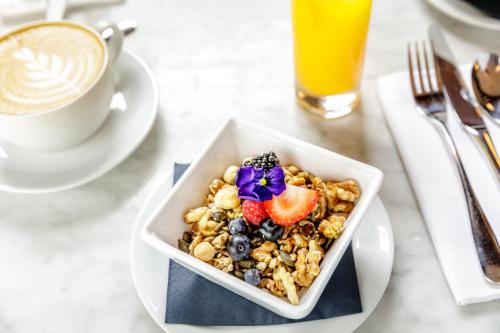 a bowl of cereal and fruit next to a cup of coffee at The Edinburgh Grand, a Luxury Collection Hotel, Edinburgh in Edinburgh