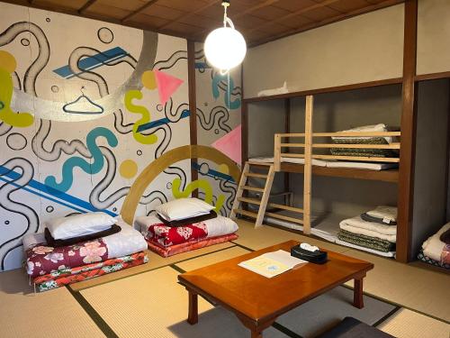 a room with two bunk beds and a table at Bakushuku Den Guest House Brew in Matsuyama