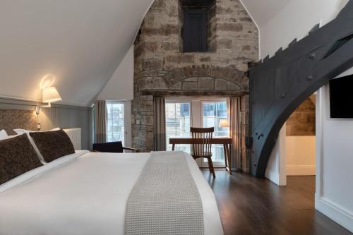 a bedroom with a large bed and a brick wall at Old Town Chambers, Autograph Collection in Edinburgh