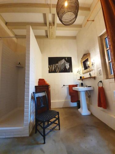 a bathroom with a shower and a sink and a chair at Gîte La Tour du Moulin in Saint-Étienne-de-Montluc