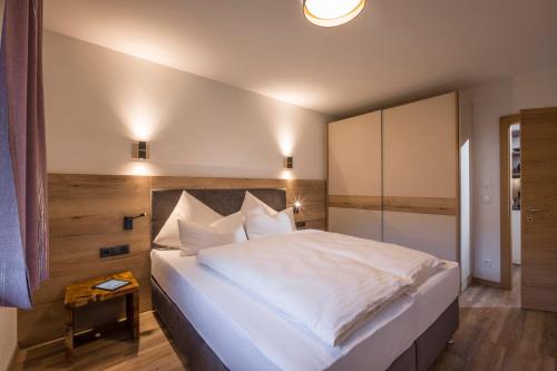 a bedroom with a large white bed with white pillows at Aparthotel AlpTirol in Kaltenbach