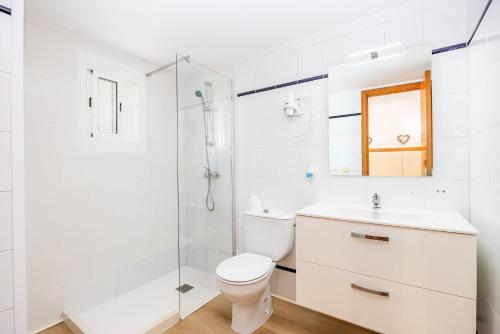 a white bathroom with a toilet and a shower at Apartamento Felipe 2-1 in Cacla D'or