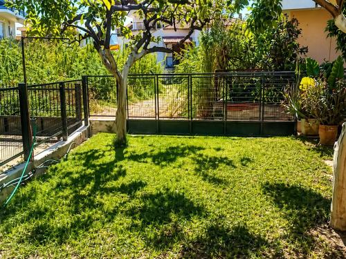 a fence with a tree in a yard at Konstantinou Apartments in Paralio Astros