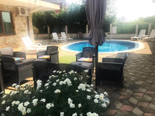 a patio with chairs and an umbrella and a pool at Апартхотел Созополски перли in Sozopol