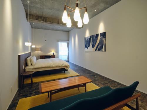 ein Schlafzimmer mit einem Bett, einem Tisch und einer Couch in der Unterkunft Arbor Onomichi in Onomichi