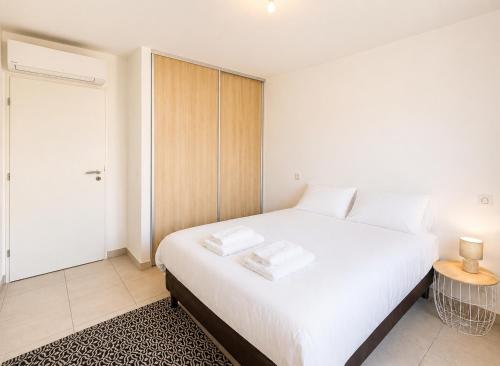 a bedroom with a large white bed and a table at Appartement Terrasse St Florent in Saint-Florent