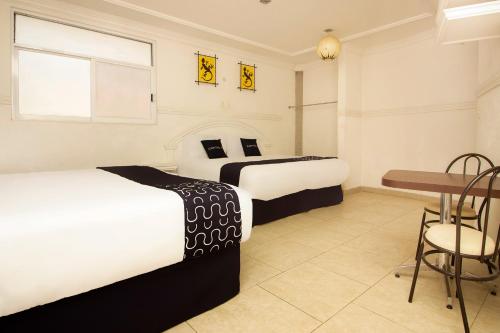 zwei Betten in einem Zimmer mit Tisch und Stühlen in der Unterkunft Capital O Hotel Partidor Del Sol, Oaxtepec in Oaxtepec