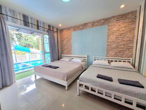 two beds in a room with a brick wall at Plus 1 2 3 Hua-Hin Private Poolvilla from beach 3km in Hua Hin