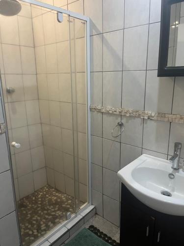 a shower with a glass door next to a sink at Ingwenya Chalet in Sodwana Bay