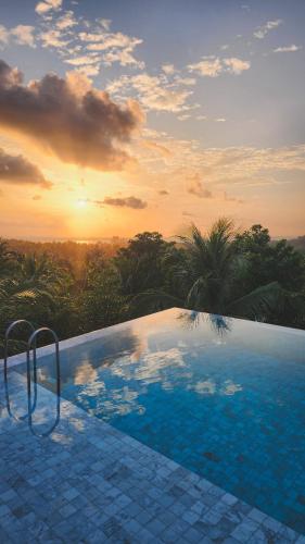 a swimming pool with a sunset in the background at Varivana Resort Koh Phangan, The Centara Collection in Thong Sala