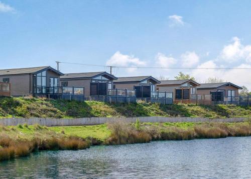 a row of houses on a hill next to a body of water at Croft Farm Water Park in Tewkesbury
