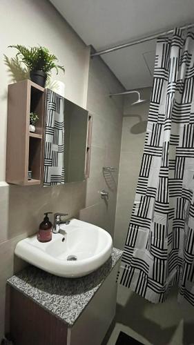 a bathroom with a sink and a shower curtain at Be Residences Studio in Cebu City