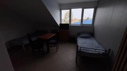 a room with a bed and a table and a window at Apartament 1 Słoneczna in Ełk