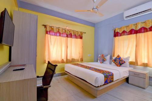 a bedroom with a bed and a desk and a television at Collection O Yellow Rose in kolkata